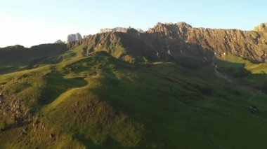 Dolomitlerin dağlarında güneşin doğuşunun hava videosu. Seiser Alm Platosu 'nda güzel bir sabah kır evleri, çayırlar ve tarlalarla. 