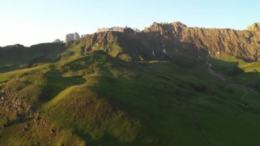 Aerial video of the sunrise in the Dolomites mountains. Beautiful morning at the Seiser Alm plateau with cottages, meadows and fields. 