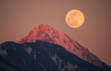 Dolunay arka planda dağlarla şehrin arkasından yükseliyor.. 