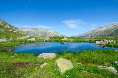 Arka planda dağlar olan göl kenarındaki manzara manzarası. Fotoğraf İsviçre 'de İsviçre Alplerinde bir dağ geçidinde çekildi..