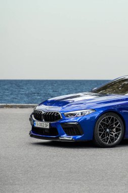 Kiev, Ukrayna - 19 Haziran 2021: Hızlı araba BMW M8 deniz ve gökyüzünün arka planına karşı yolda