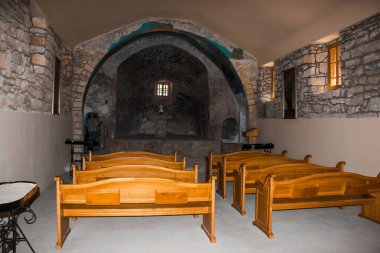 İçerideki eski kilise. Tahta banklar ve taş duvarlar