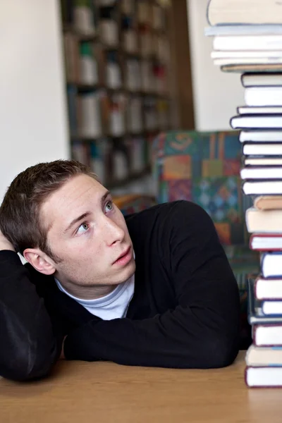 Student blickt zu Bücherstapel auf — Stockfoto