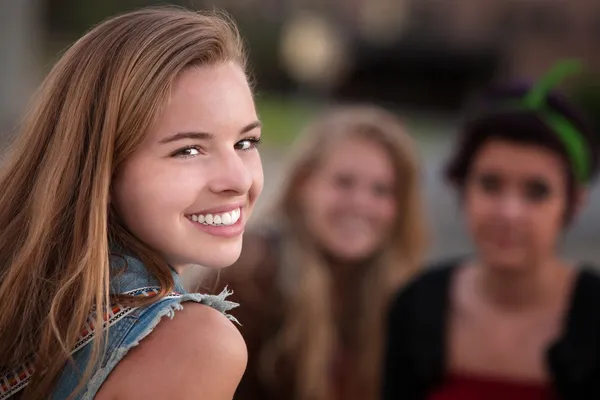 Sorrindo adolescente menina com dois amigos — Fotografia de Stock