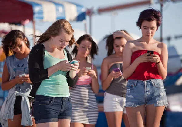 Jonge dames met behulp van hun telefoons Stockafbeelding