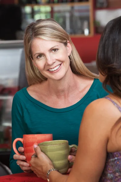 Sarışın bir kadın arkadaşıyla bistro gülümseyen — Stok fotoğraf