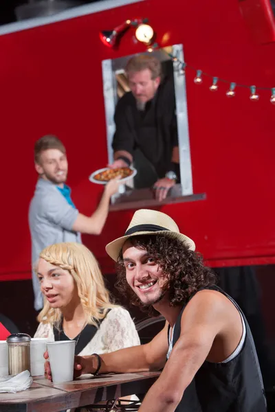 Hombre sonriente con amigos en camión de comida — Foto de Stock