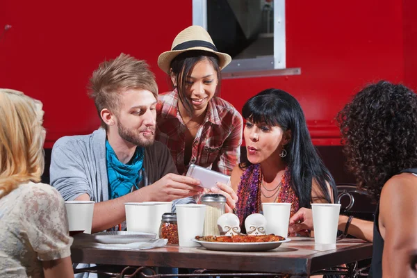 Amigos comiendo y mirando el teléfono — Foto de Stock