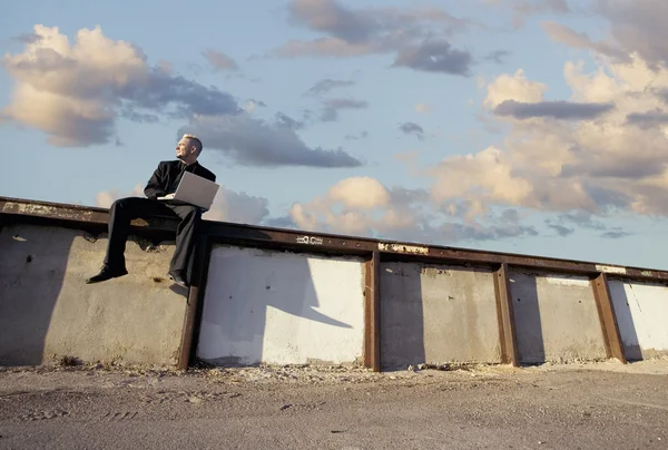 Uomo d'affari punk su un muro con computer portatile — Foto Stock