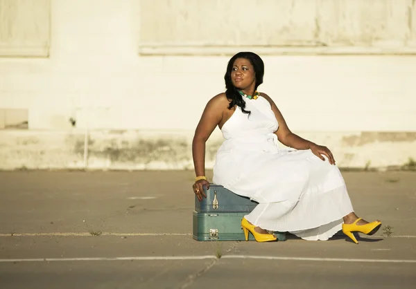 Афроамериканка сидит на чемоданах — стоковое фото