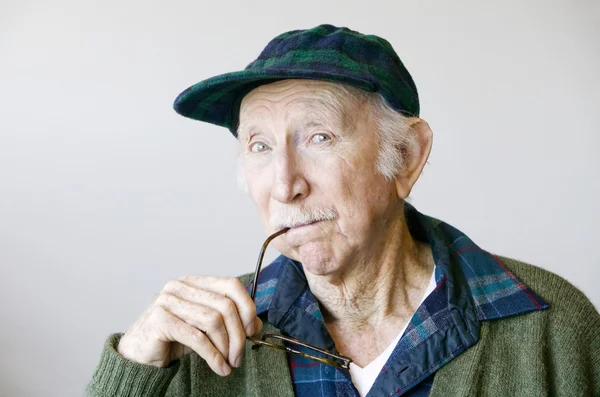 Doordachte senior man in een hoed en bril — Stockfoto