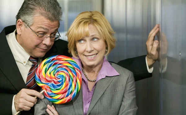 Man in office offers coworker a lollipop — Stock Photo, Image