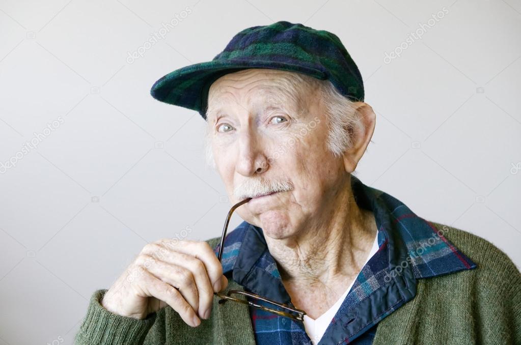 Thoughtful Senior Man in a Hat and Glasses