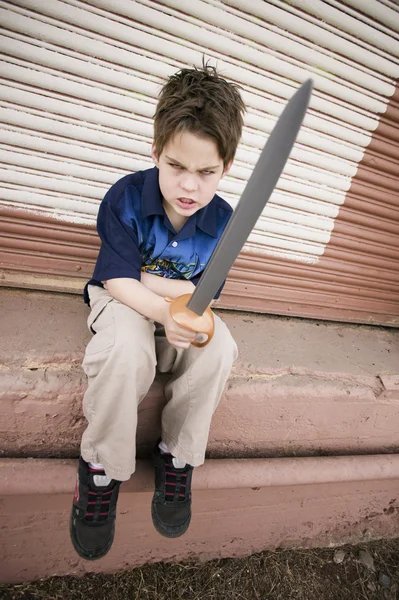 Rapaz irritado com uma espada de brinquedo — Fotografia de Stock
