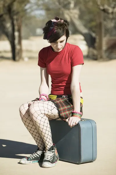 Панк-девушка, сидящая на чемодане — стоковое фото