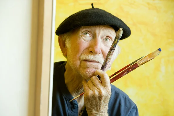Kunstenaar met een baret op een doek opzoeken — Stockfoto