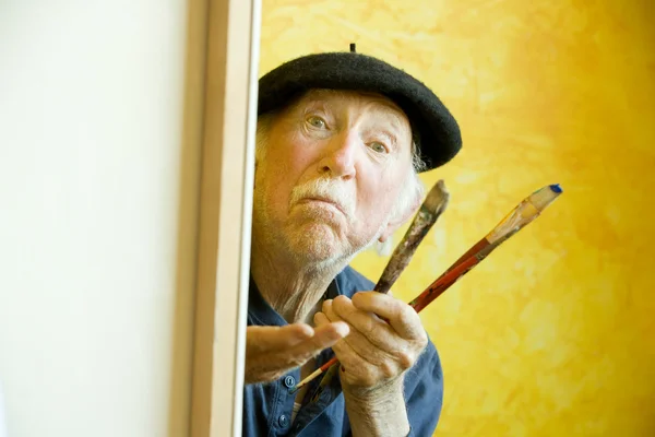 Umělec s baret na plátno, při pohledu na model — Stock fotografie
