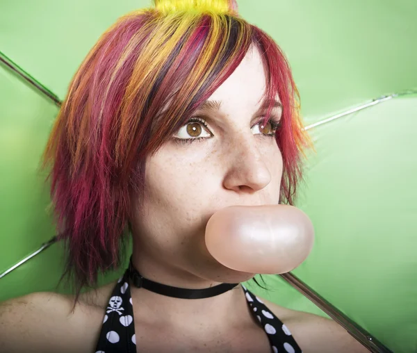 Mulher bonita com um guarda-chuva verde soprando uma bolha — Fotografia de Stock