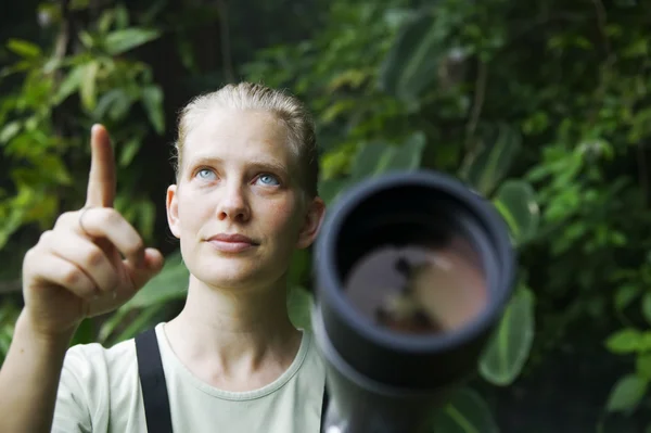 Vacker kvinna med teleskop i regnskogen — Stockfoto