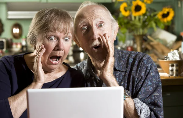 Casal Senior chocado com um computador portátil — Fotografia de Stock