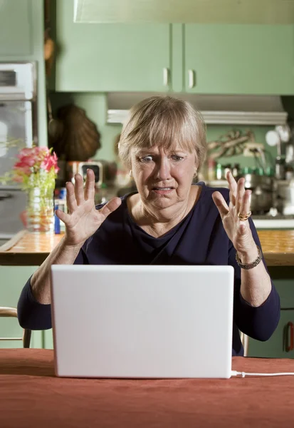 Chocado Senior Woman com um computador portátil — Fotografia de Stock