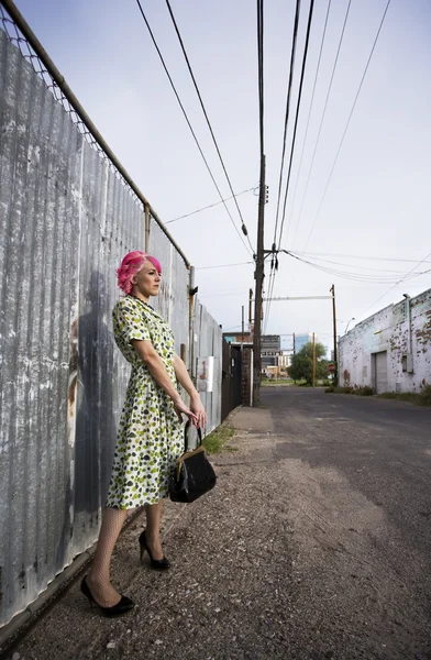 Mulher com cabelo rosa e uma bolsa em um beco — Fotografia de Stock