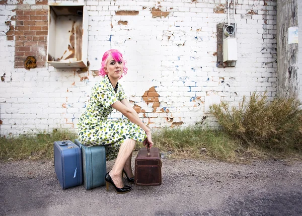 Женщина с розовыми волосами и маленькими Siuitcases — стоковое фото