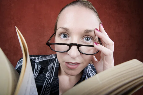 Peprlexed mulher com grandes olhos lendo um livro — Fotografia de Stock