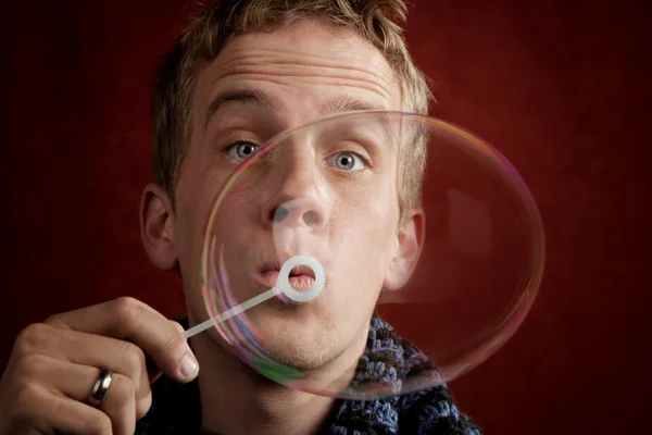 Молодой человек, надувающий пузырь — стоковое фото