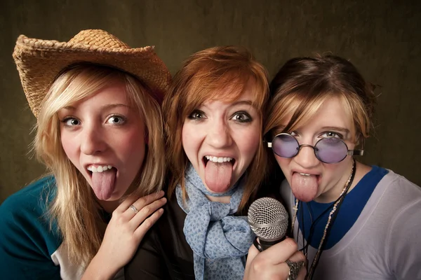 三个年轻女孩与麦克风和吐着舌头 — 图库照片