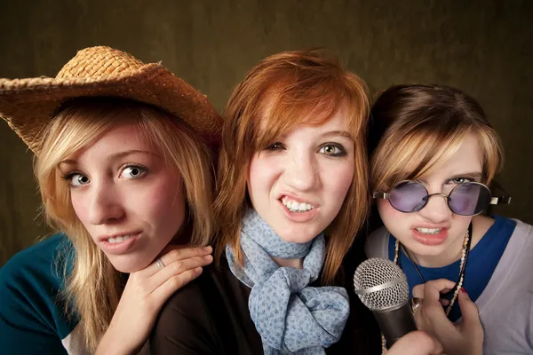 Drie jonge meisjes met microfoon waardoor gezichten — Stockfoto