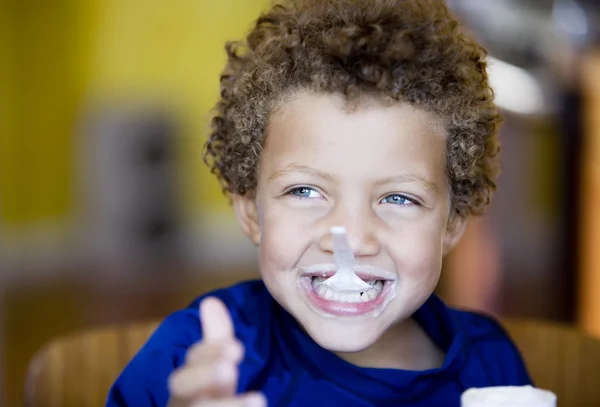 Boy with blue eyes eating yogurt — Stock Photo, Image
