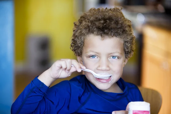 Boy with blue eyes eating yogurt — Stock Photo, Image
