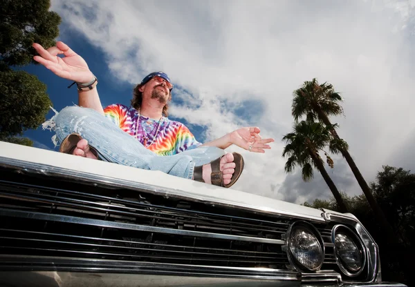 Hippie mediterar på bil huva — Stockfoto