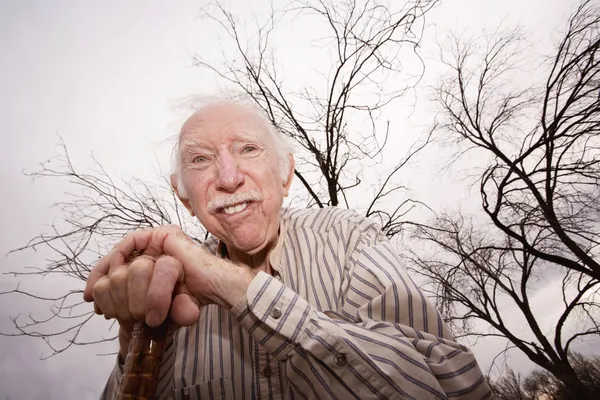 Oude man voor kale bomen — Stockfoto