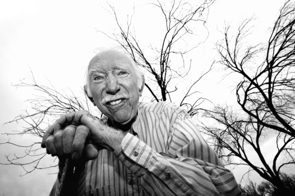 Oude man voor kale bomen — Stockfoto