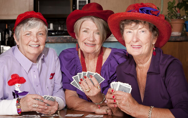 Ladies wearing red hats playing cards
