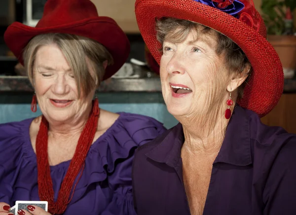 Mesdames portant des chapeaux rouges jouant aux cartes — Photo