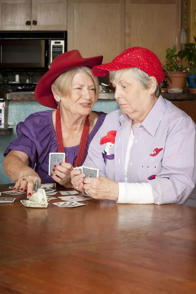 Damen mit roten Hüten spielen Karten — Stockfoto