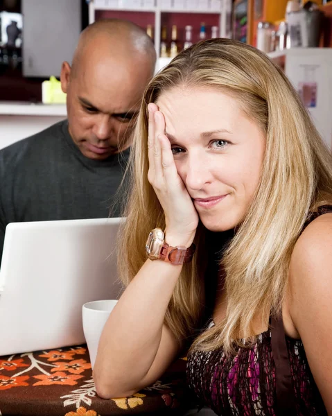 Mujer aburrida con el hombre en el ordenador portátil — Foto de Stock