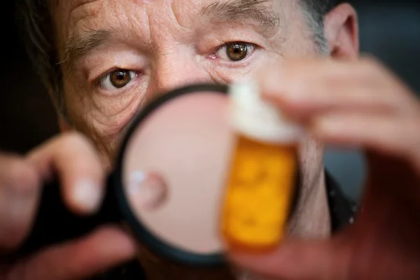 Uomo esaminando le istruzioni sulla bottiglia medicina — Foto Stock