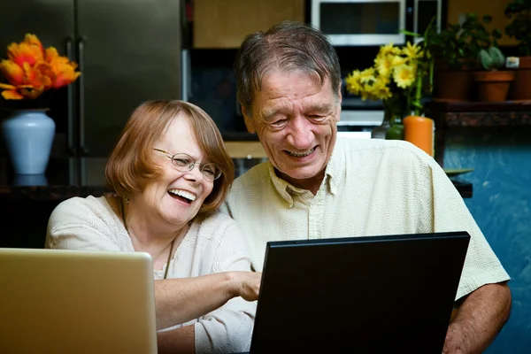 Pareja mayor usando computadoras portátiles en casa —  Fotos de Stock