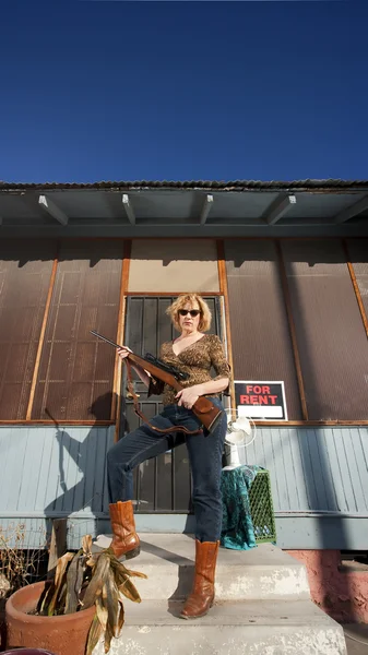 Wanita di depan proch dengan senapan — Stok Foto