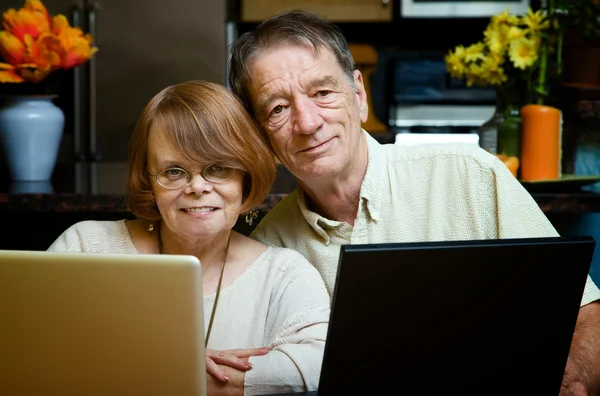 Casal sênior usando computadores portáteis em casa — Fotografia de Stock