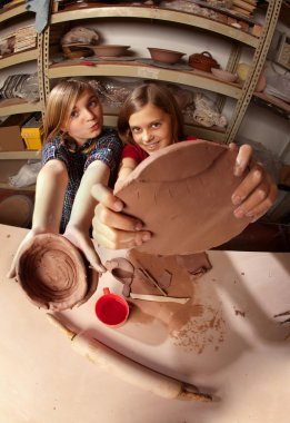Cute young girls in a clay studio clipart