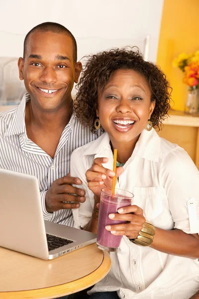 Young couple smile as they work on a laptop — Stock Photo, Image