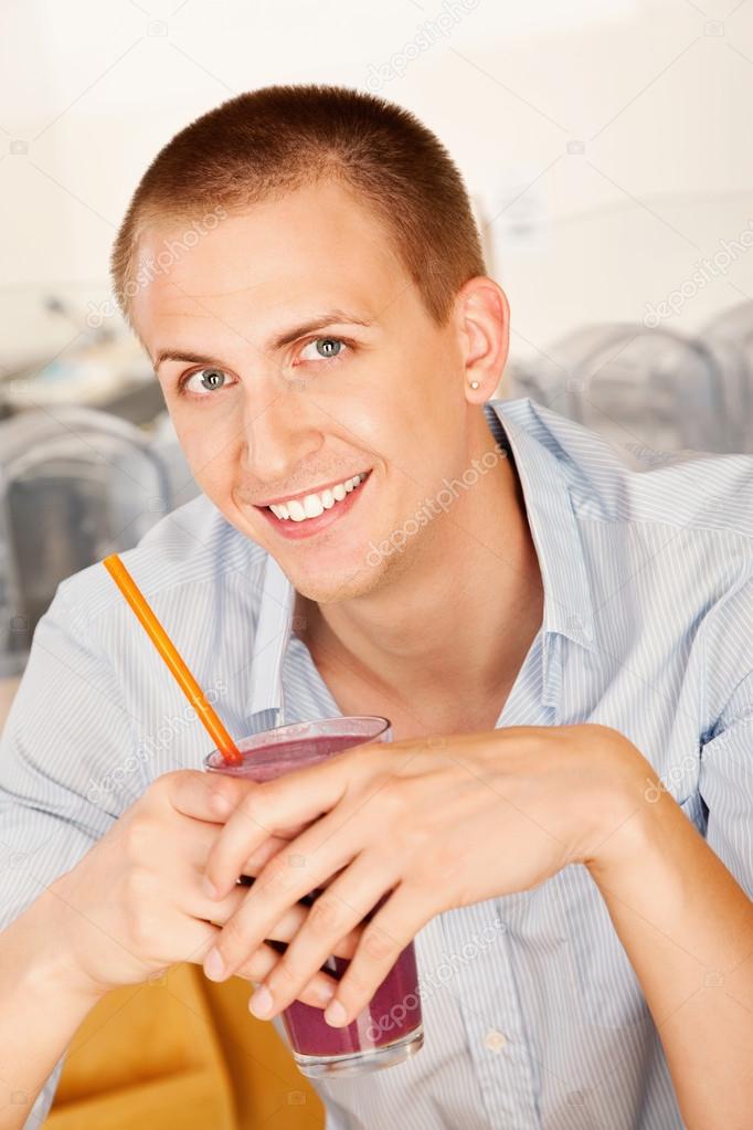 A young man holding a frozen beverage.