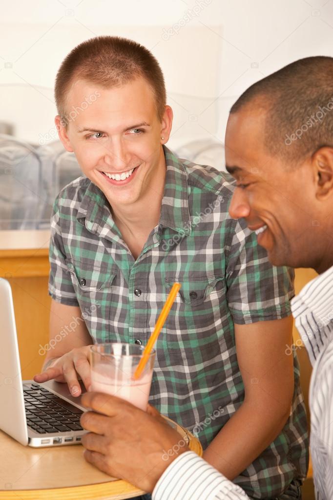 Young men at a cafe using a laptop computer.