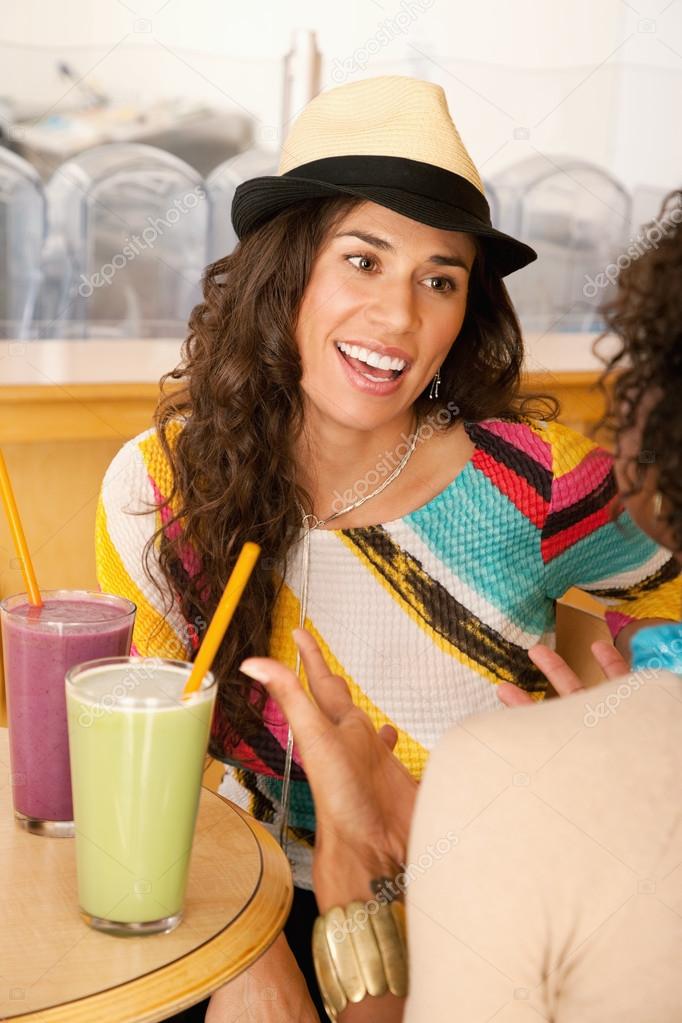 Two young women at a cafe drinking frozen beverages