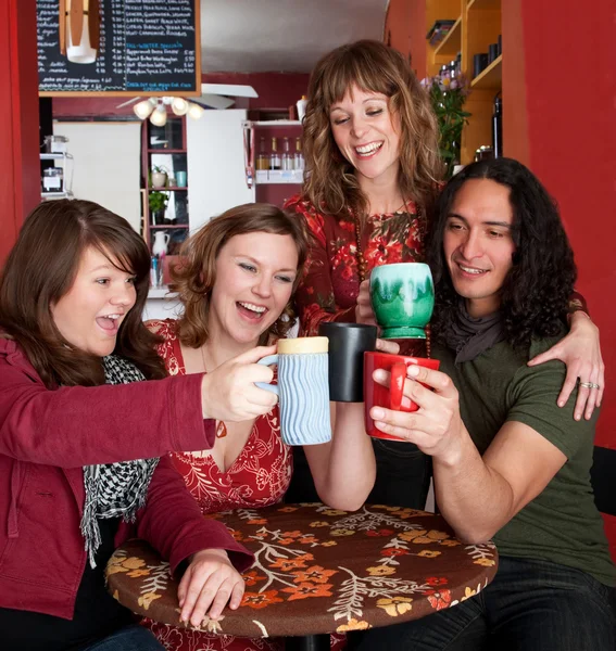 Quatro jovens amigos brindam em um café — Fotografia de Stock